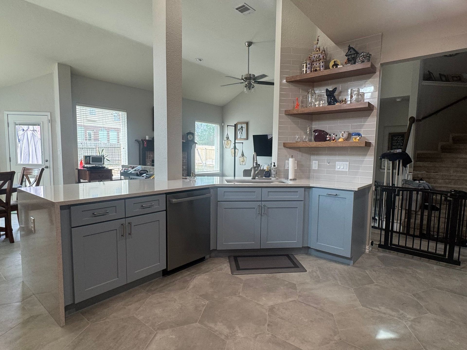 Modern kitchen with gray cabinets, white countertops, island, and open shelving in a bright home interior