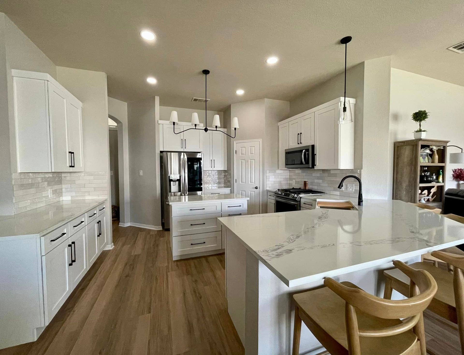 Bright modern kitchen with white cabinets, central island, wood floors, and stainless steel appliances