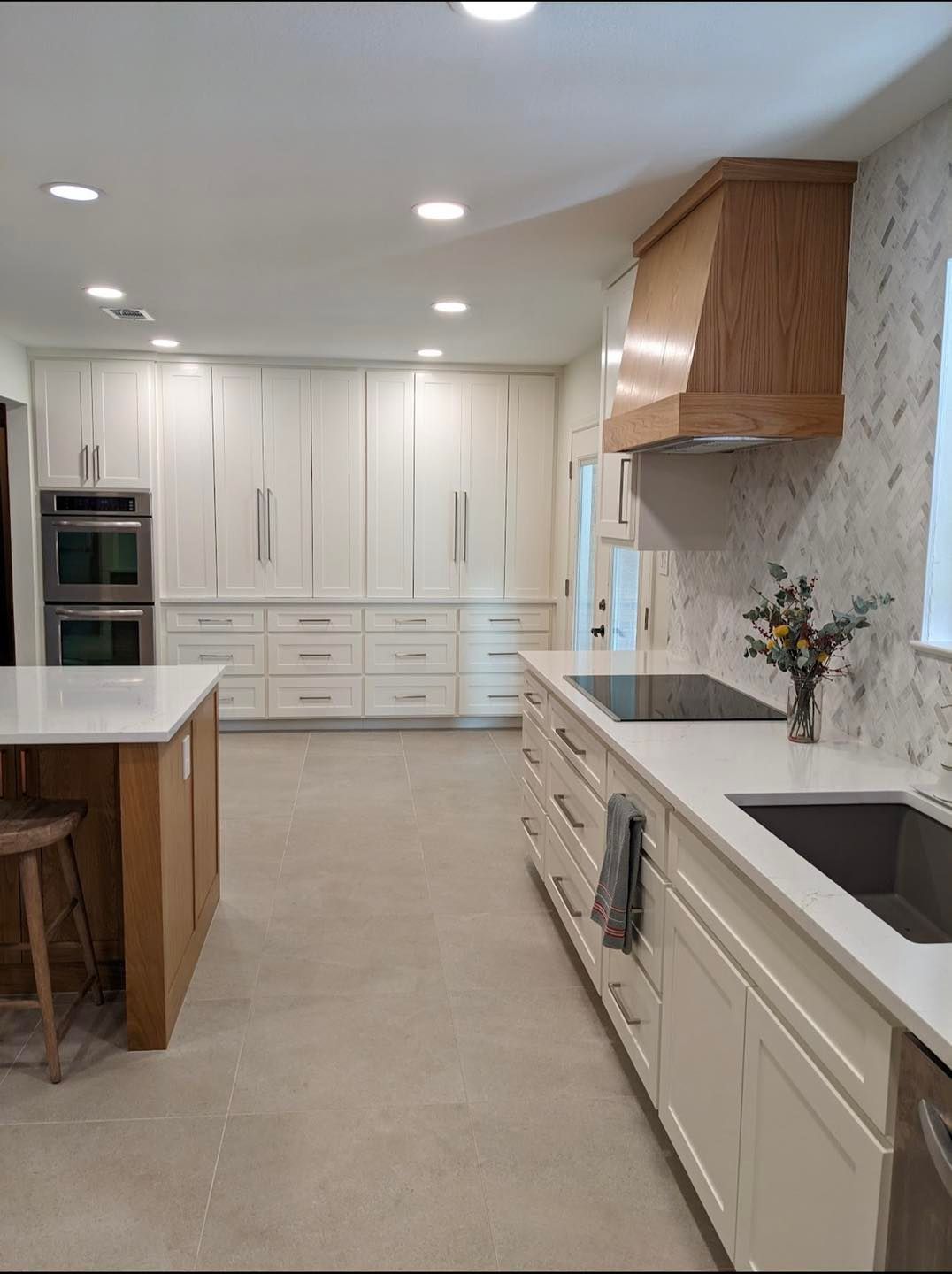 Bright, modern white kitchen with island, wood accents, and built-in appliances