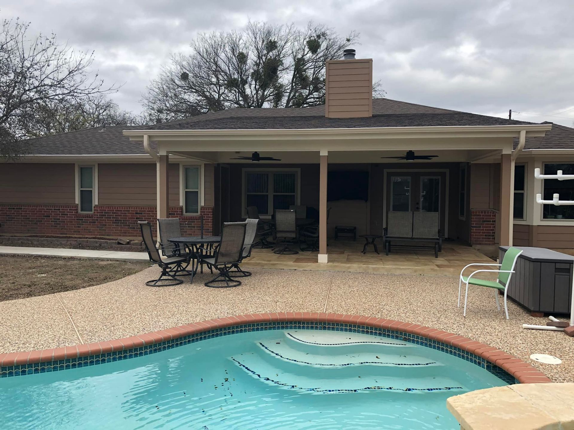 Backyard patio with covered porch, patio furniture, and a swimming pool in the foreground