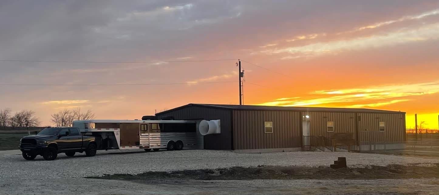 Pickup truck beside a long cabin at sunset under a colorful sky