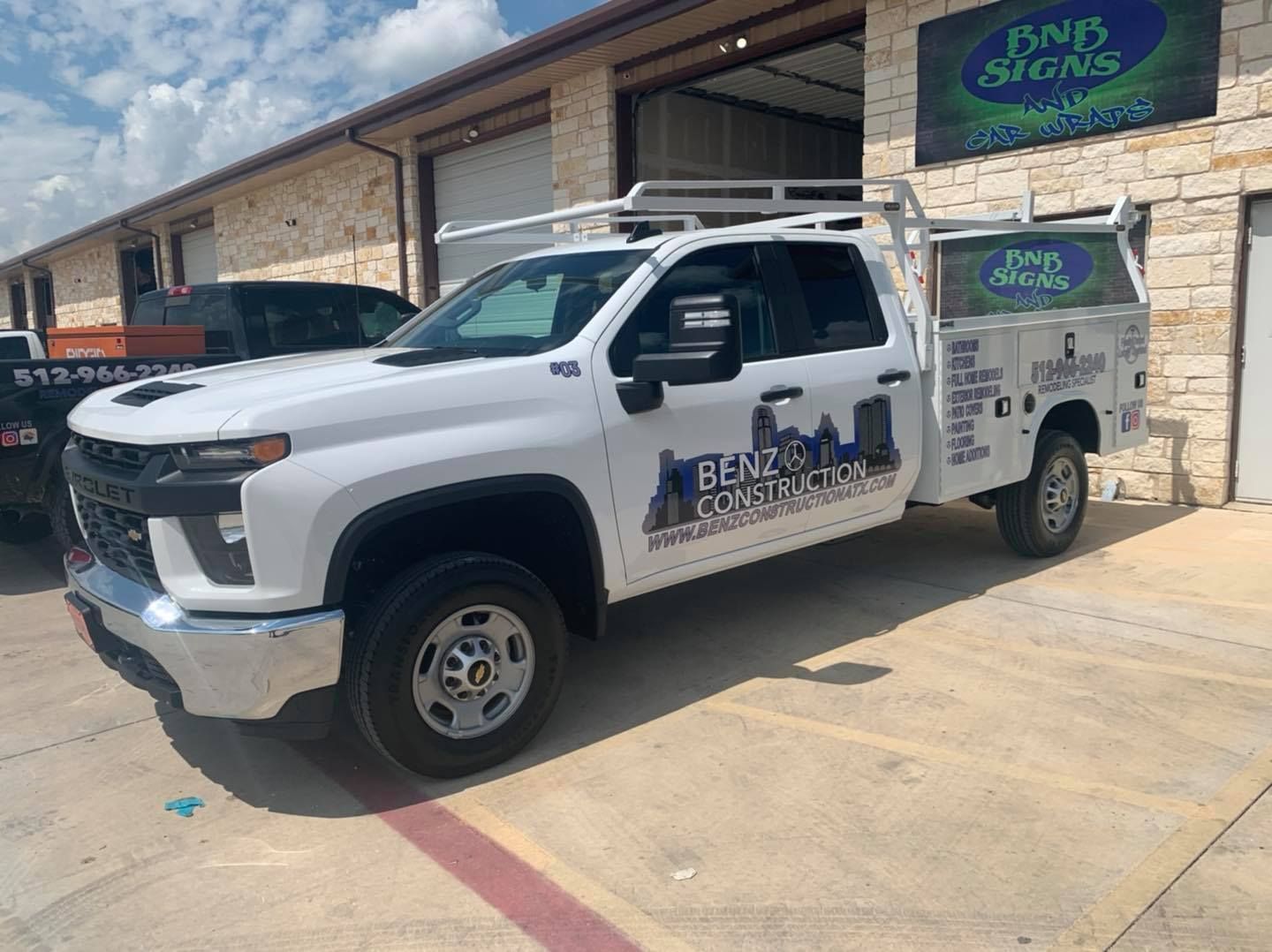 White service truck parked outside a stone building in bright daylight