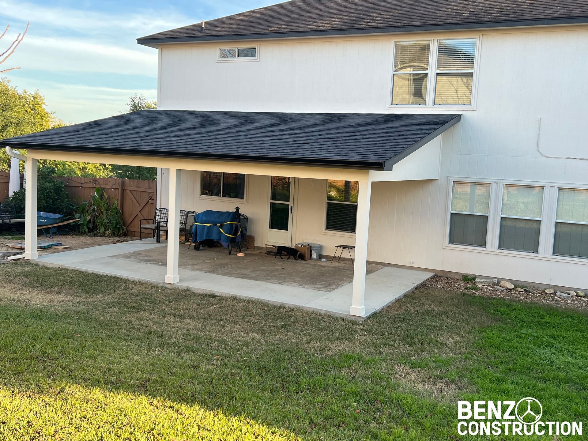 Back patio covered with white awning on a two-story house, overlooking a grassy yard.