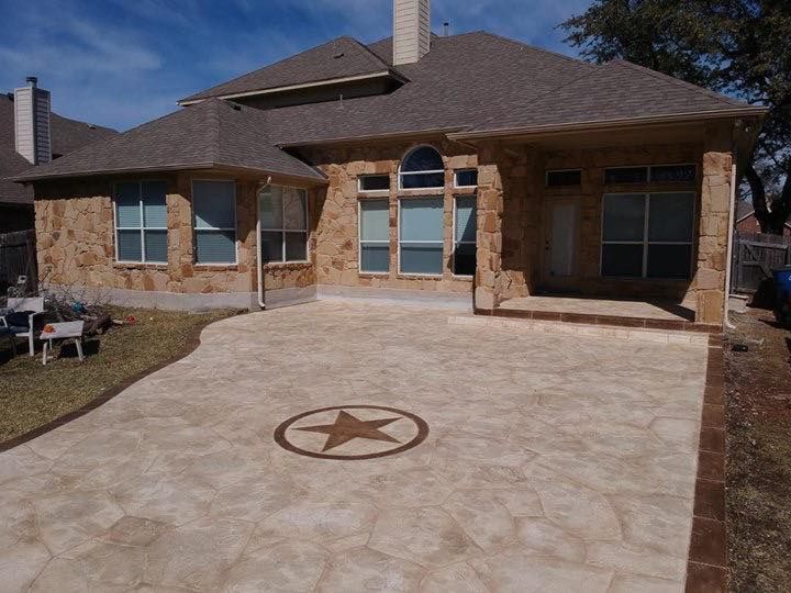 Brick house with arched windows and a stamped concrete driveway featuring a star medallion.