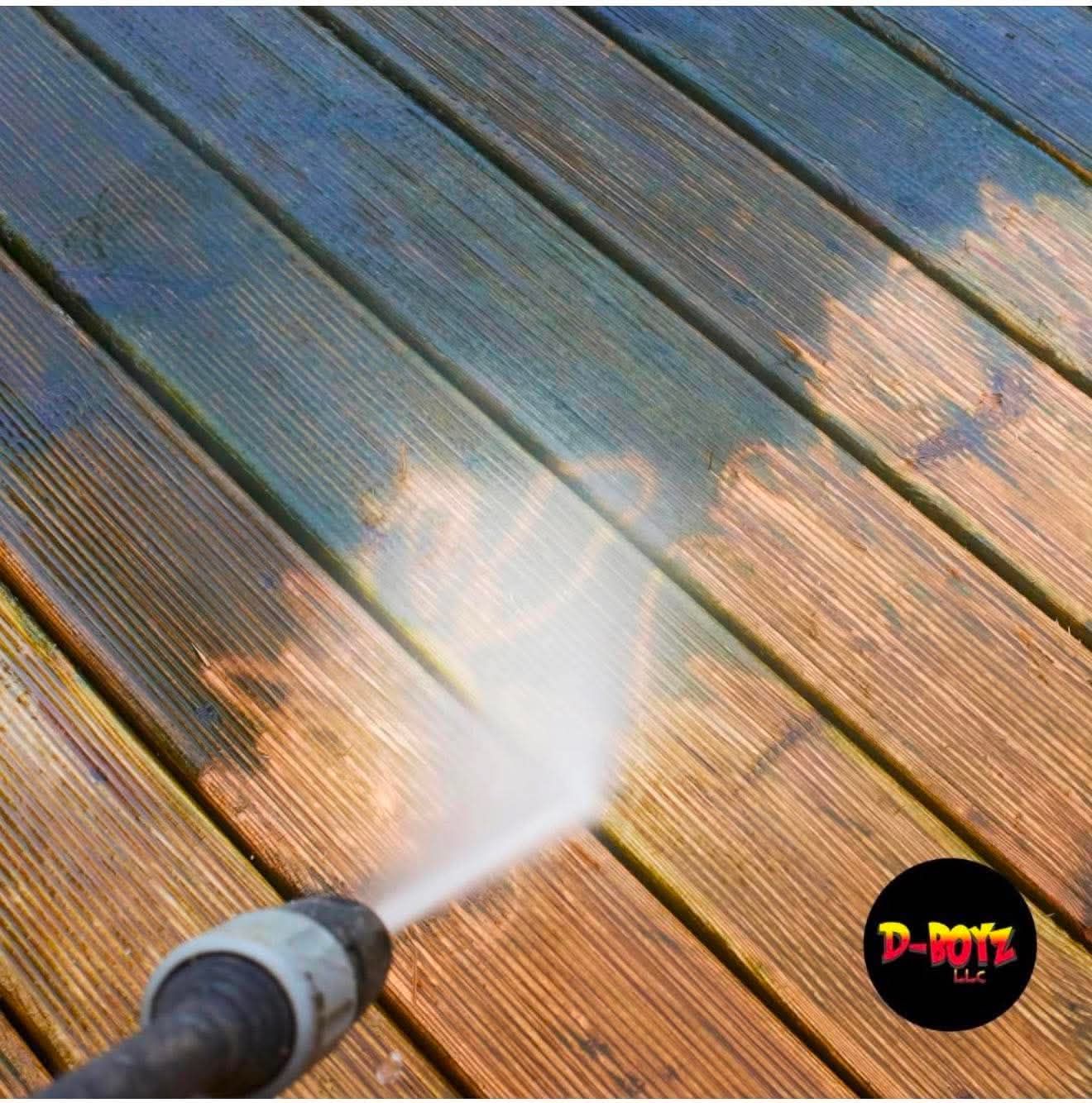 Pressure washing a weathered wooden deck, spraying off dirt and grime