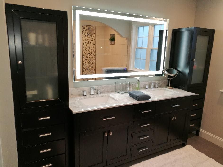 Black bathroom vanity with a lighted mirror, flanked by storage cabinets.