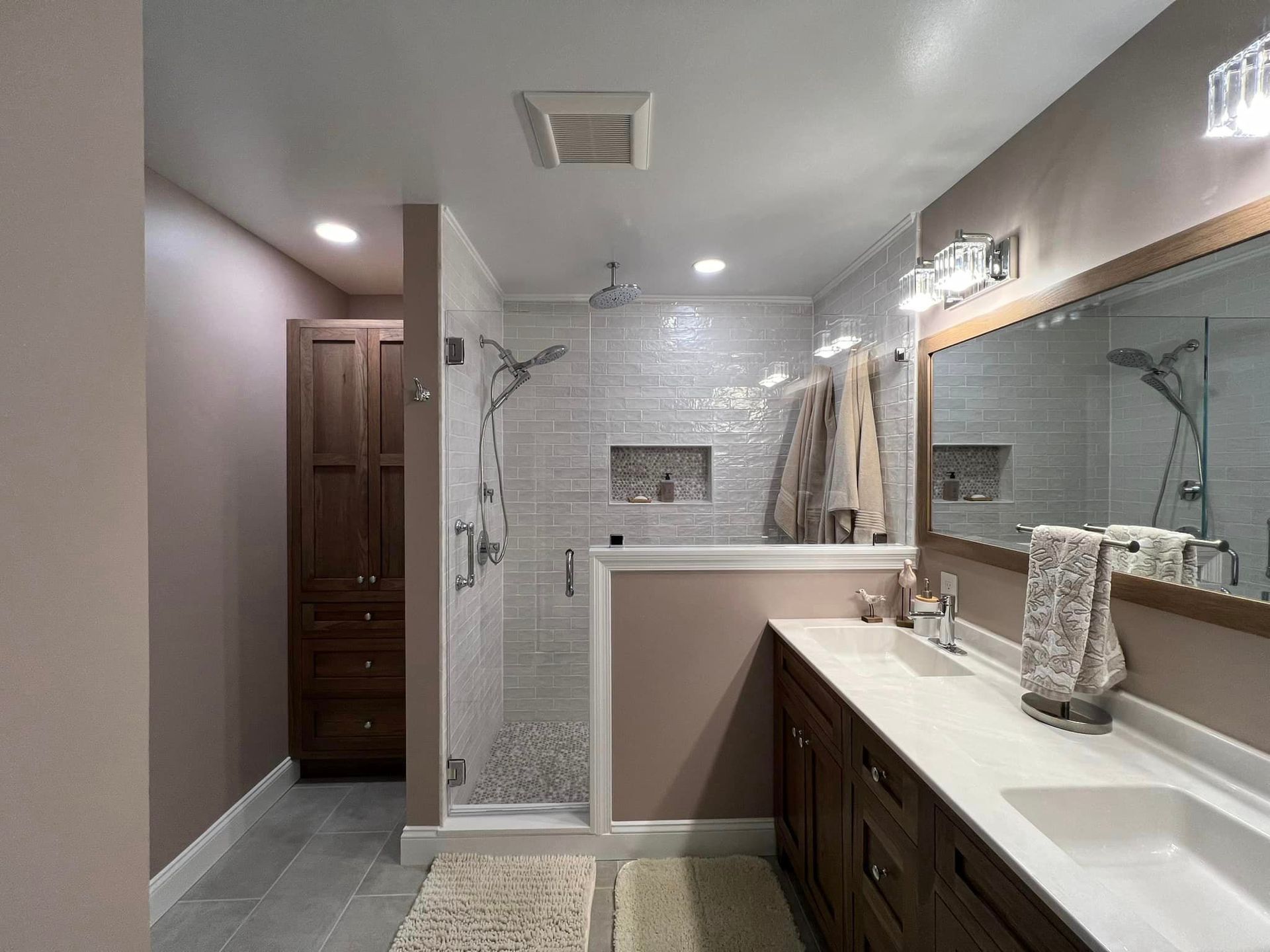 A bathroom with a walk in shower, sink and mirror.