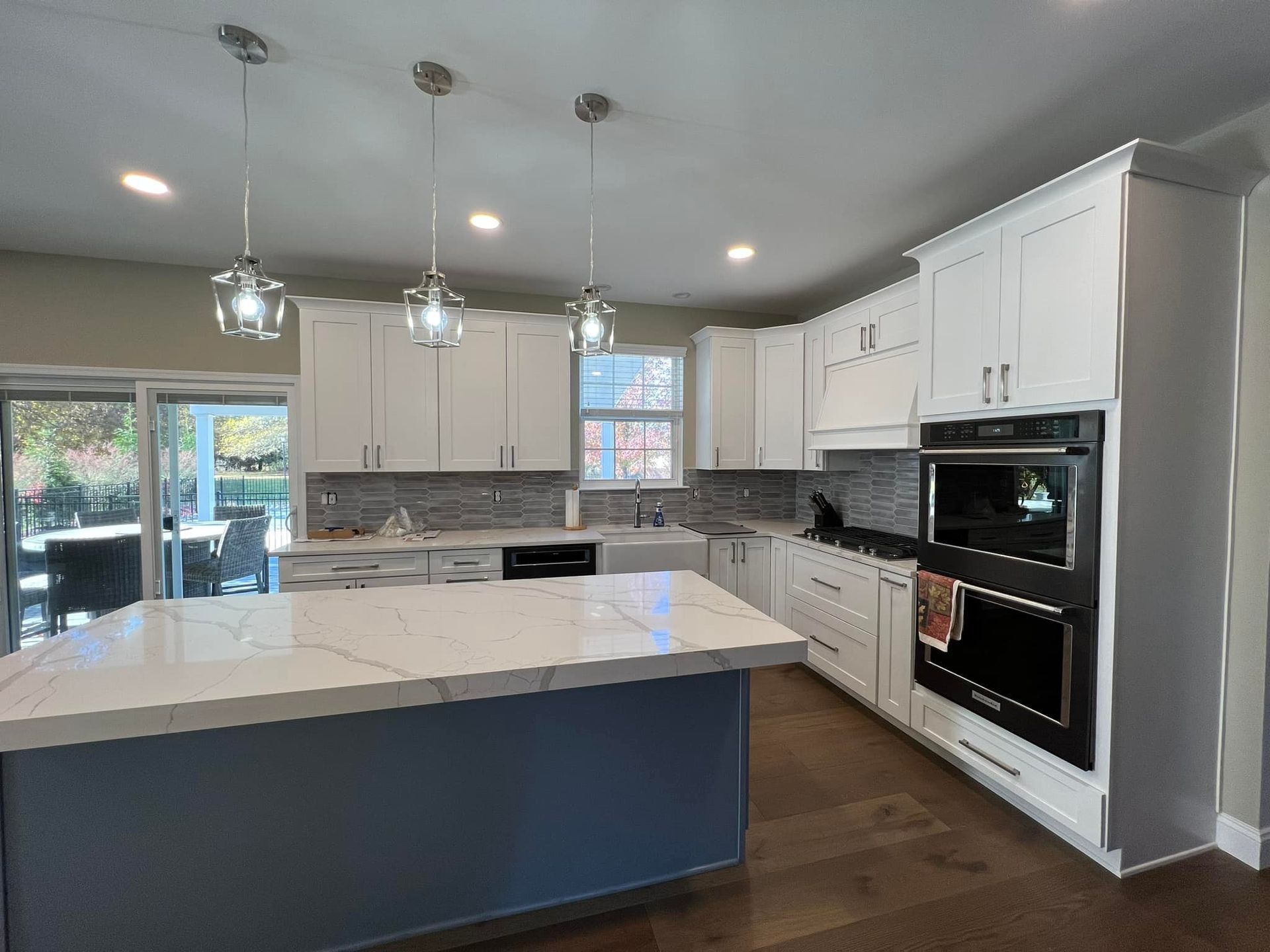 A kitchen with white cabinets and a blue island.
