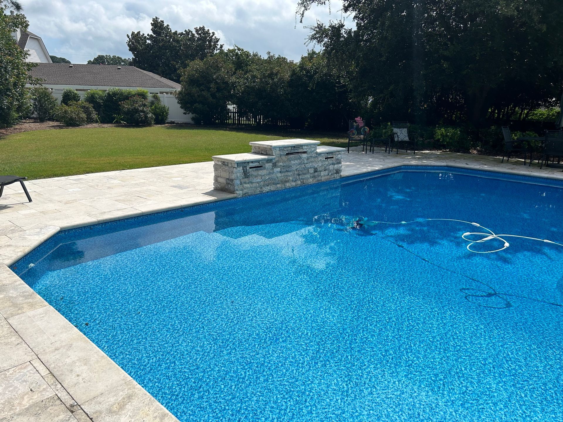 a large swimming pool is surrounded by a lush green lawn