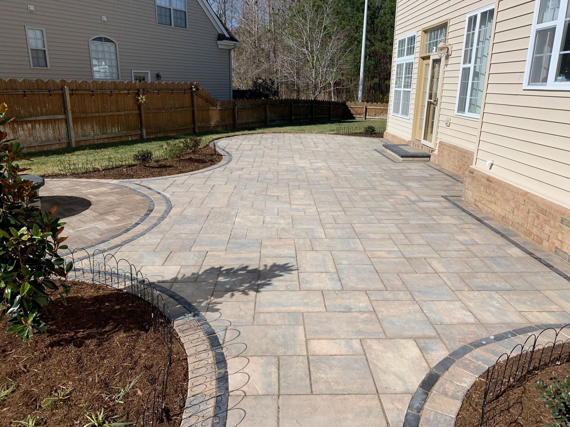 a patio with a fence in the background and a house in the background