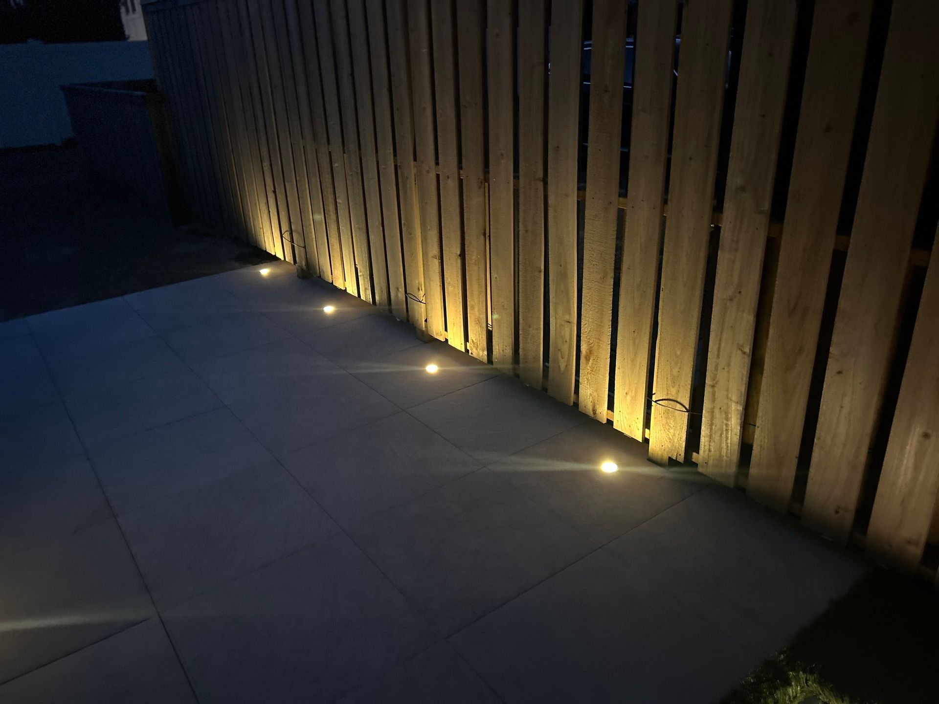 a wooden fence with lights on the side of it at night