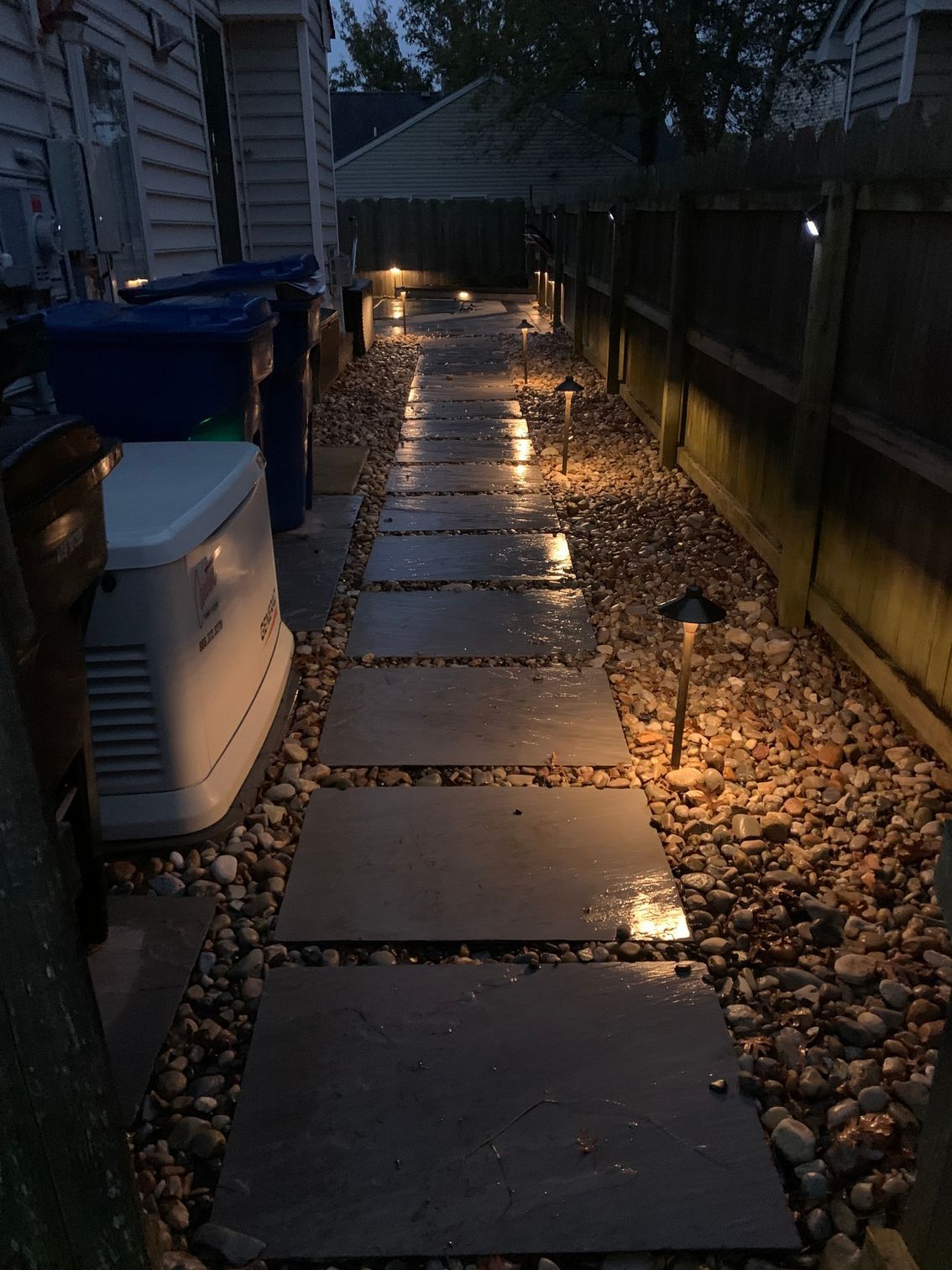 a stone walkway leading to a house is lit up at night