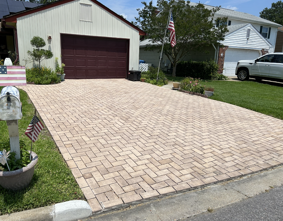 a white car is parked in front of a house with a brick driveway