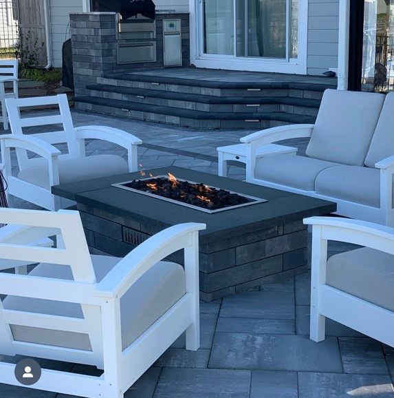 a patio with white chairs and a fire pit