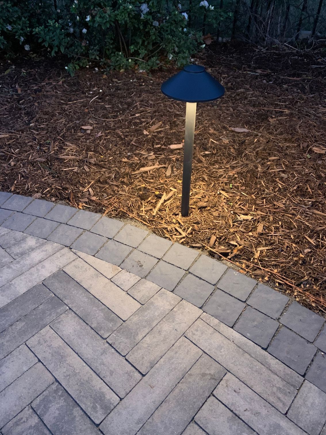 a brick walkway with a light on the side of it