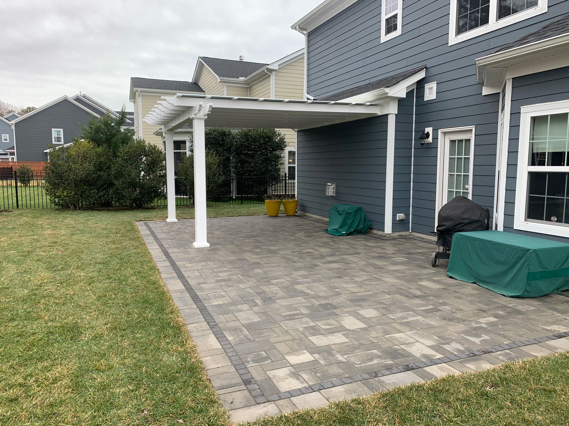 a patio with a pergola and a grill in front of a house