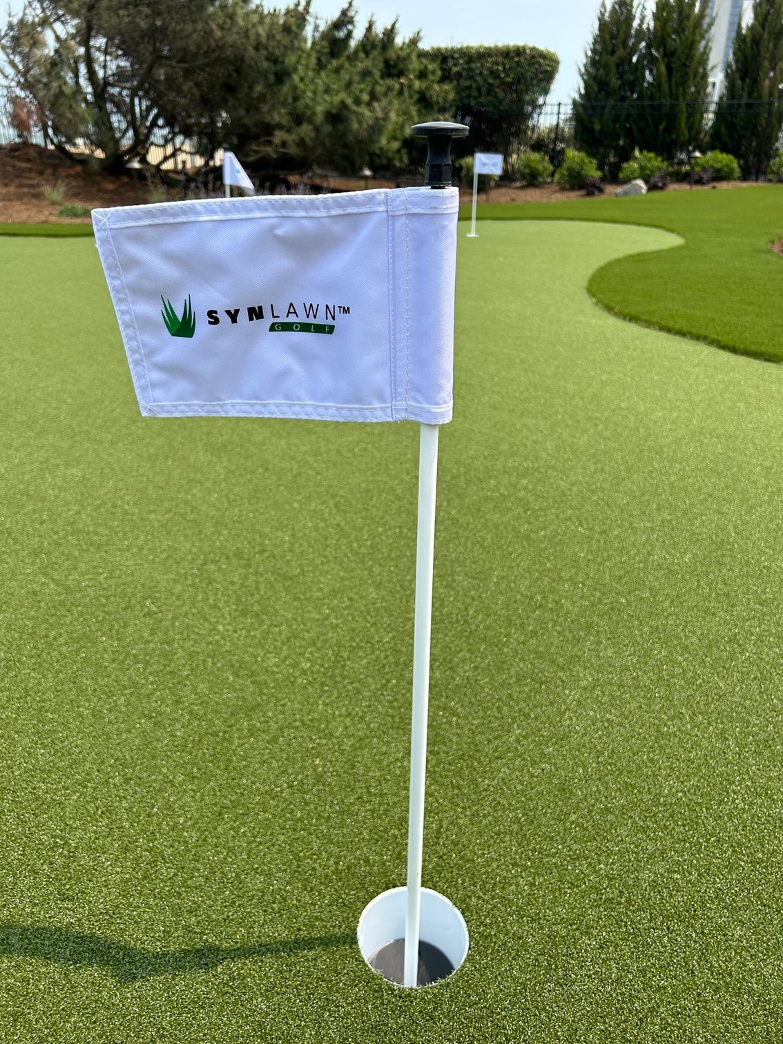a white golf flag is sitting on top of a green golf course