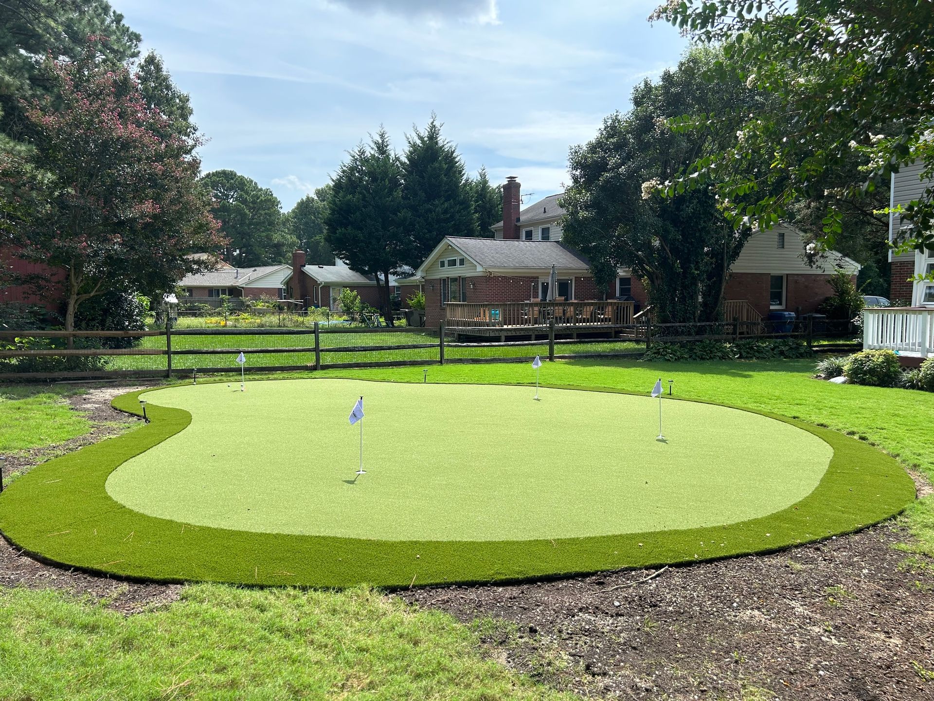a putting green in a backyard with a house in the background