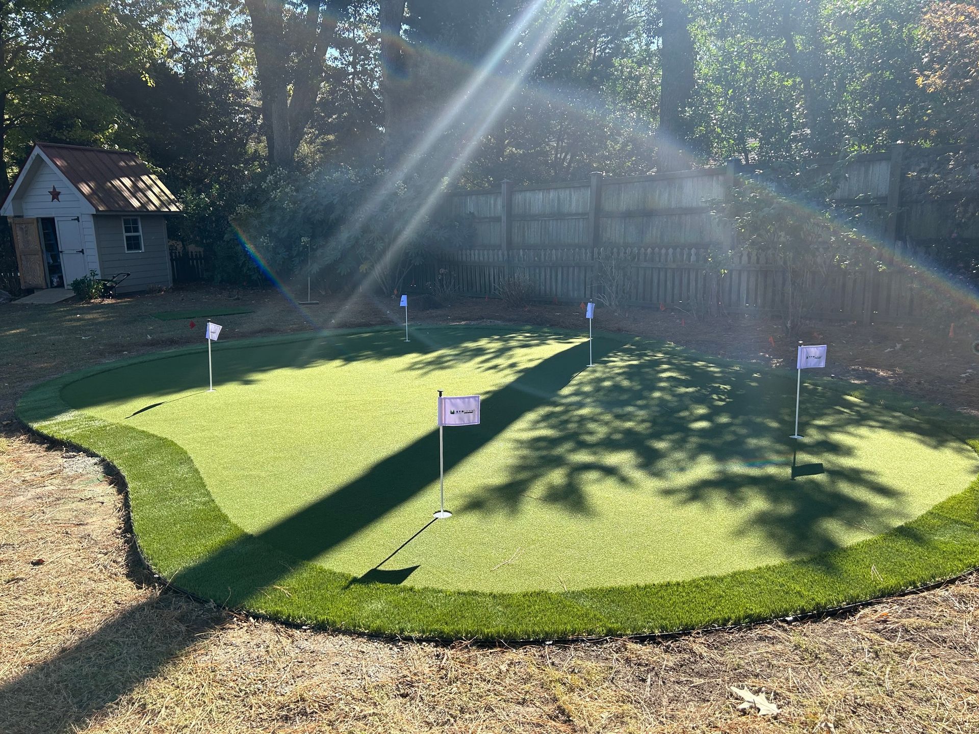 a putting green in a backyard with a house in the background