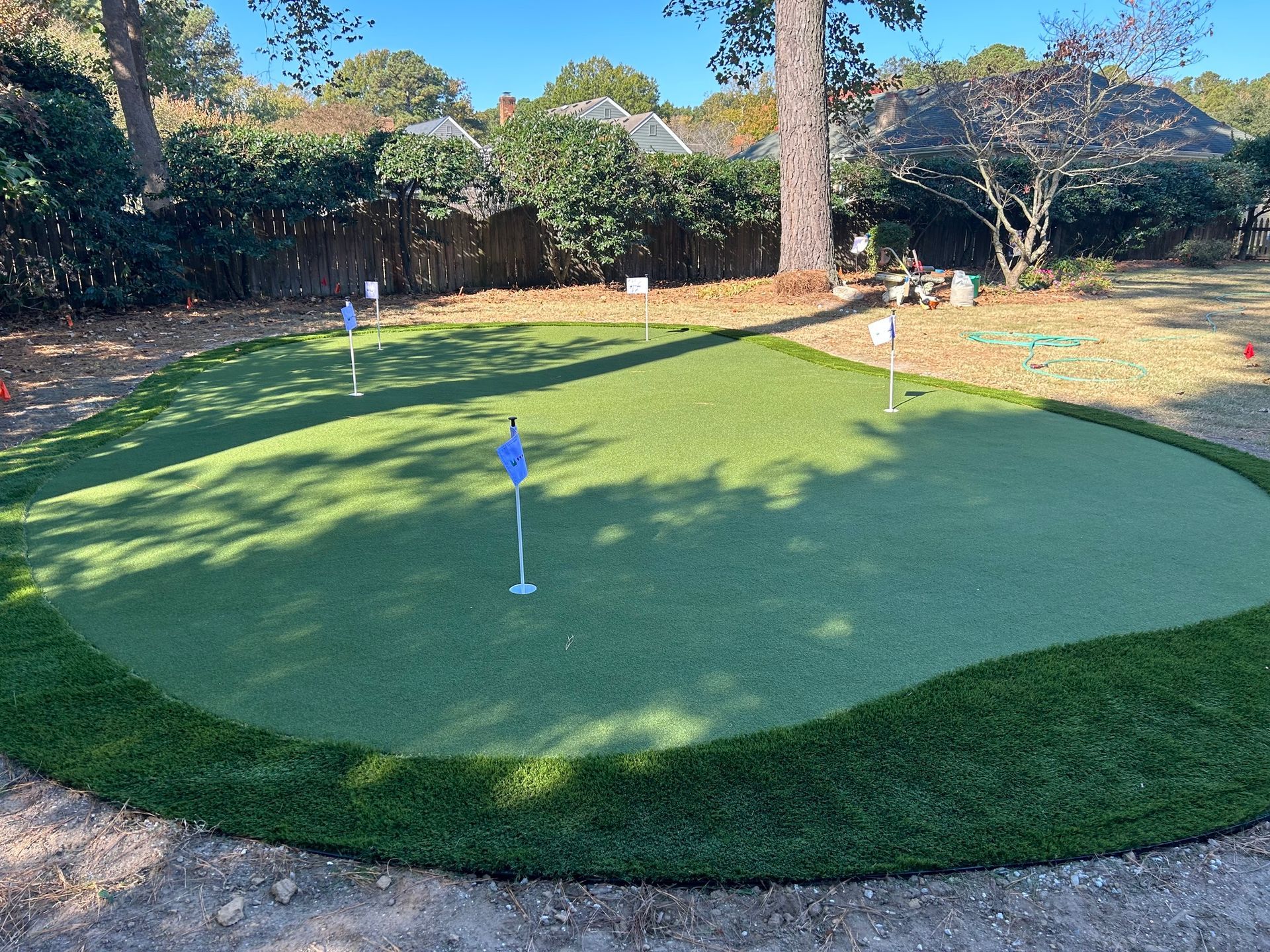 a putting green in a backyard with trees in the background