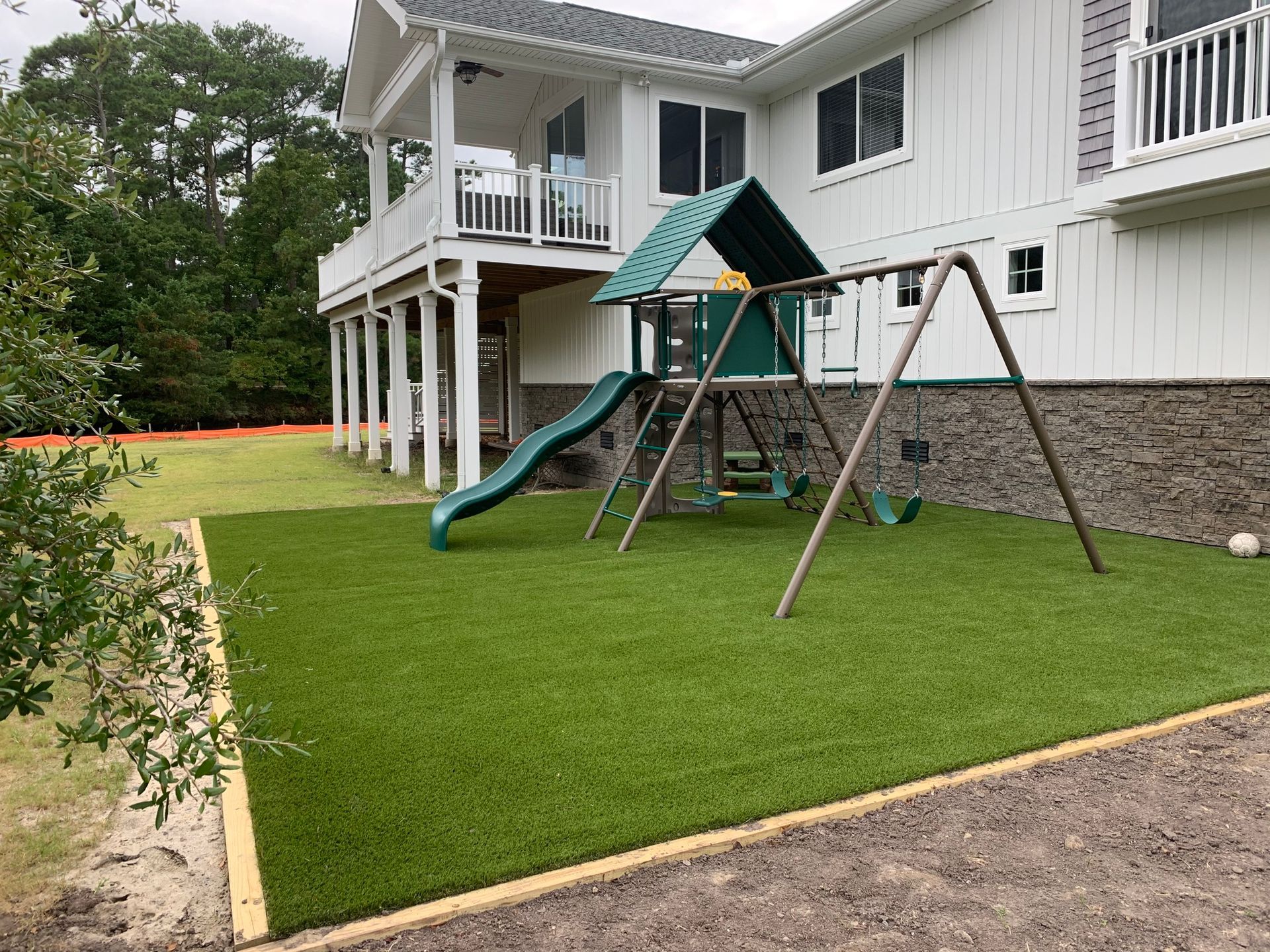 a backyard with a swing set and a slide in front of a house