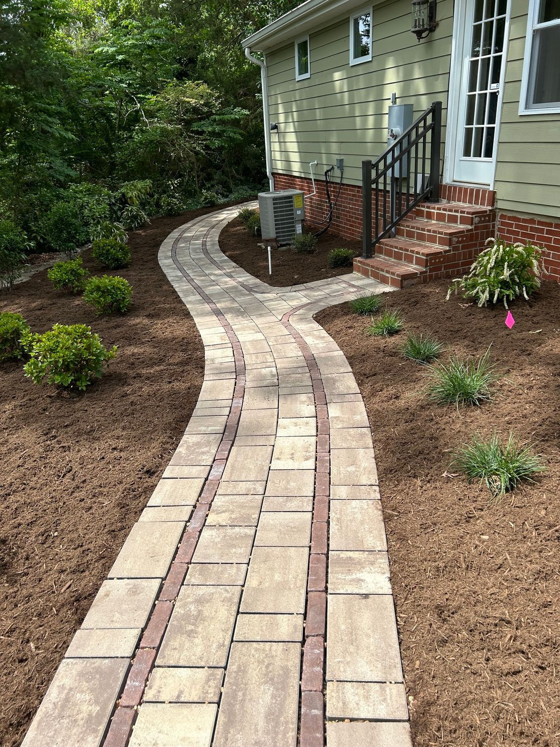 a brick walkway leading to a house with stairs