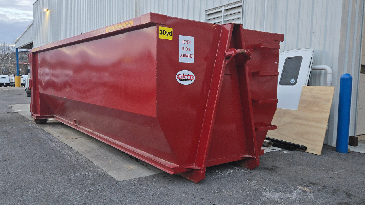 A large red dumpster is parked in front of a building