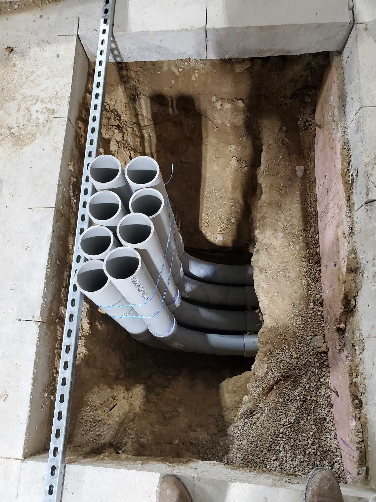 A bunch of pipes are in a hole in the ground.
