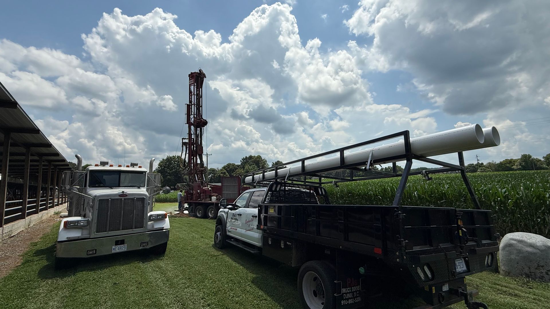 A truck is parked in a grassy field next to a drilling rig.
