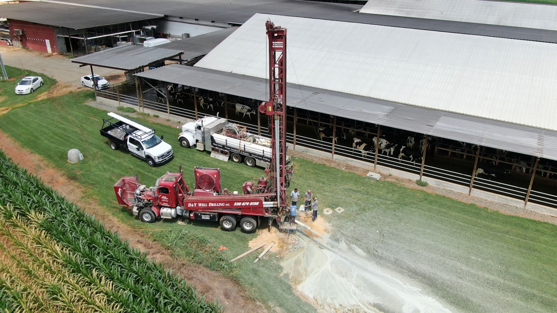 An aerial view of a drilling rig in a field in front of a farm.