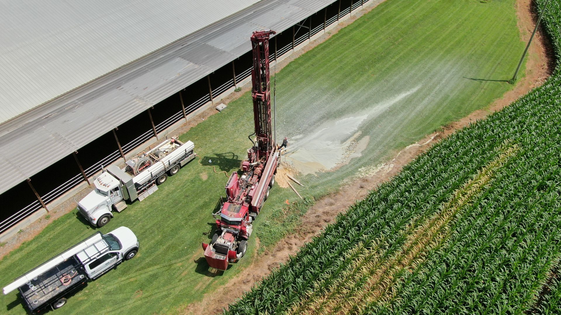 An aerial view of a drilling rig in a field of corn.