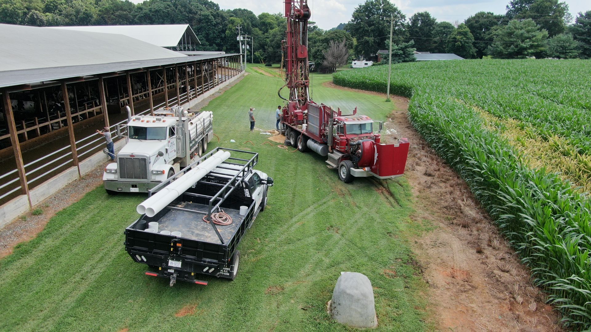 A couple of trucks are parked in a field next to a barn.