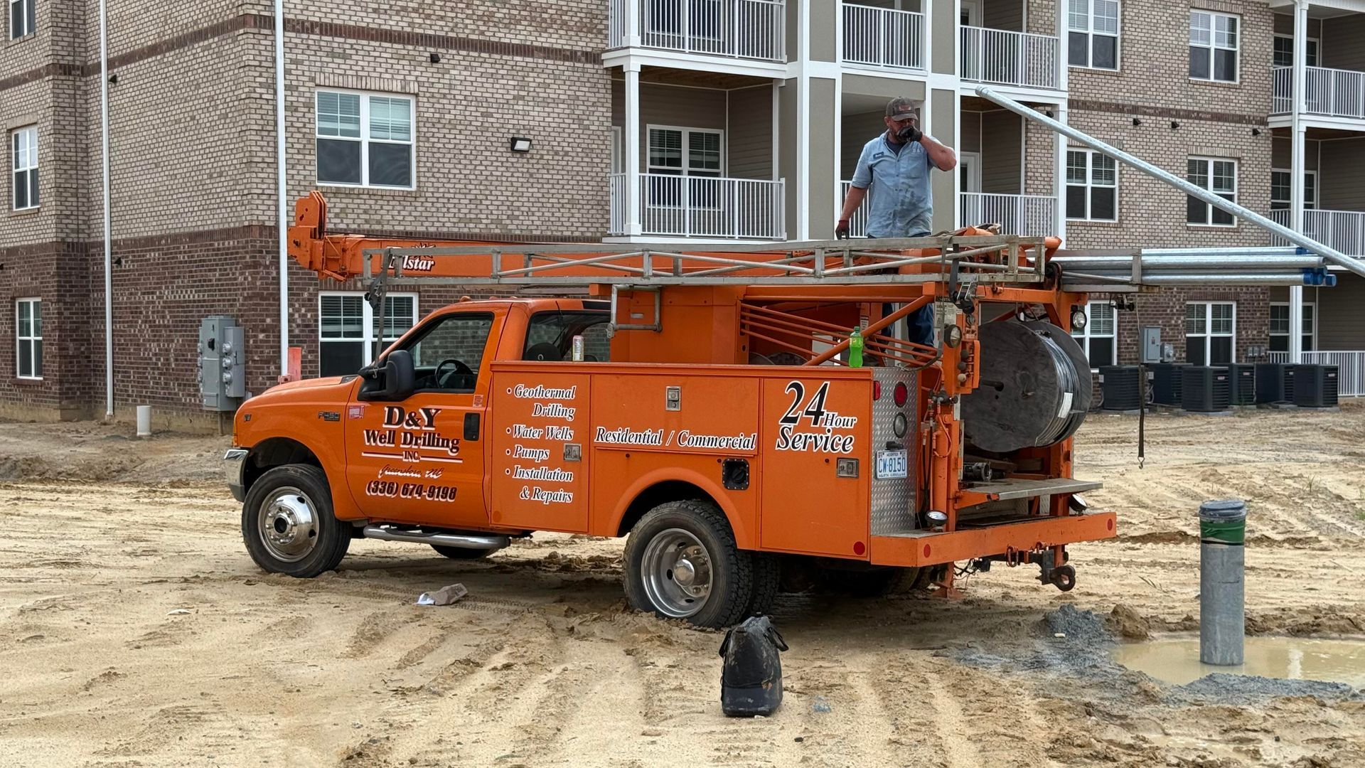 An orange truck is parked in front of a brick building.