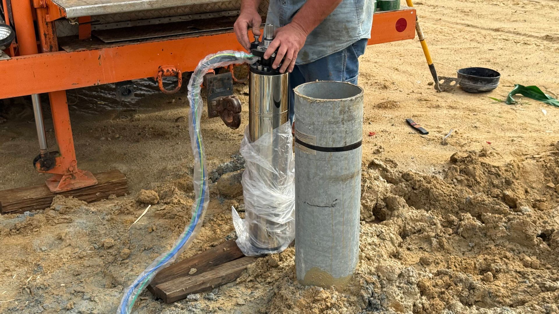 A man is pumping water into a concrete pipe.