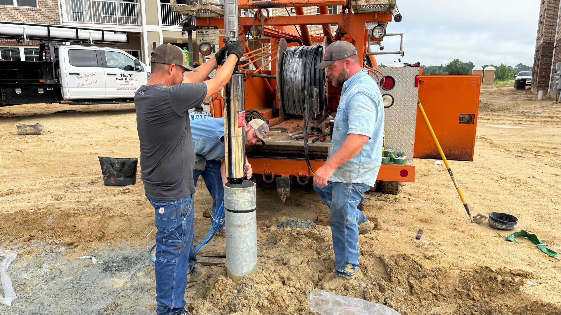 Two men are working on a machine in the dirt.