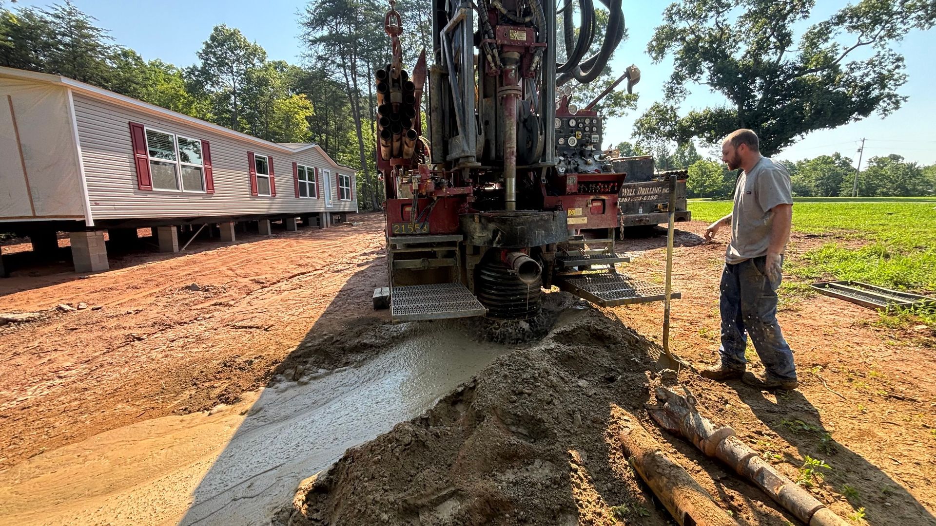 A man is standing next to a machine that is drilling a hole in the ground.