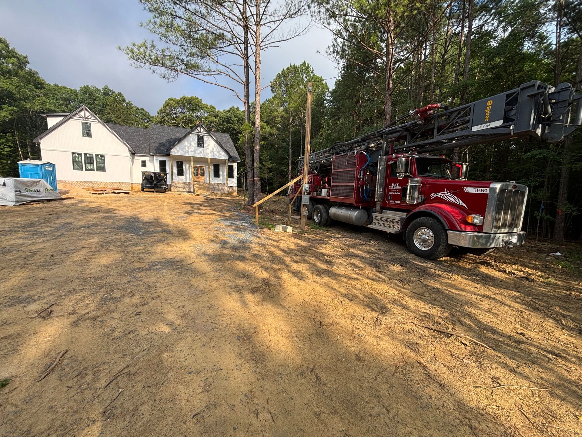 A red truck is parked in front of a house under construction.