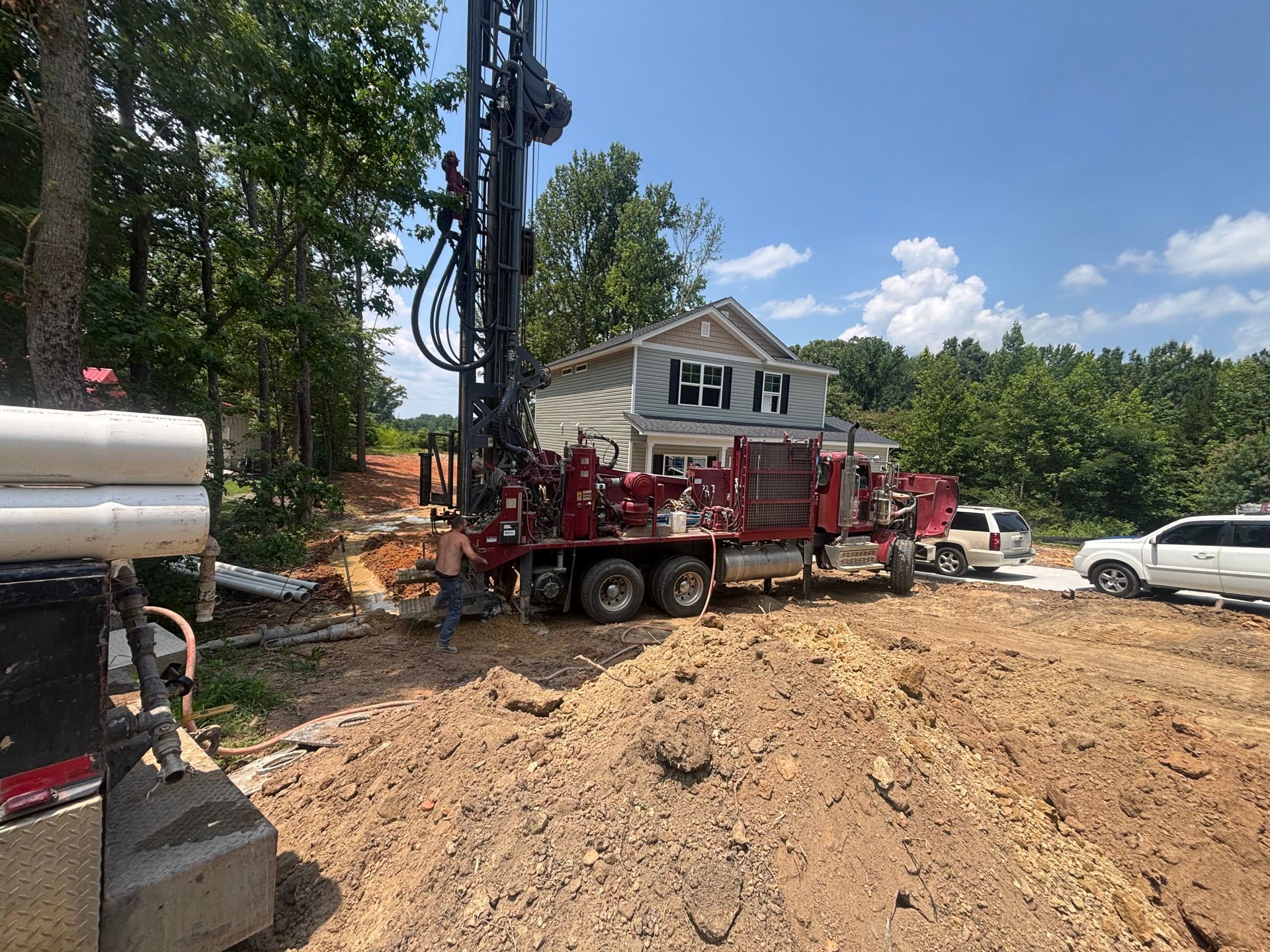 A truck is driving down a dirt road in front of a house.