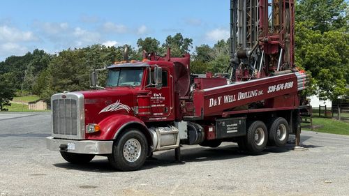 A red semi truck is parked in a gravel lot