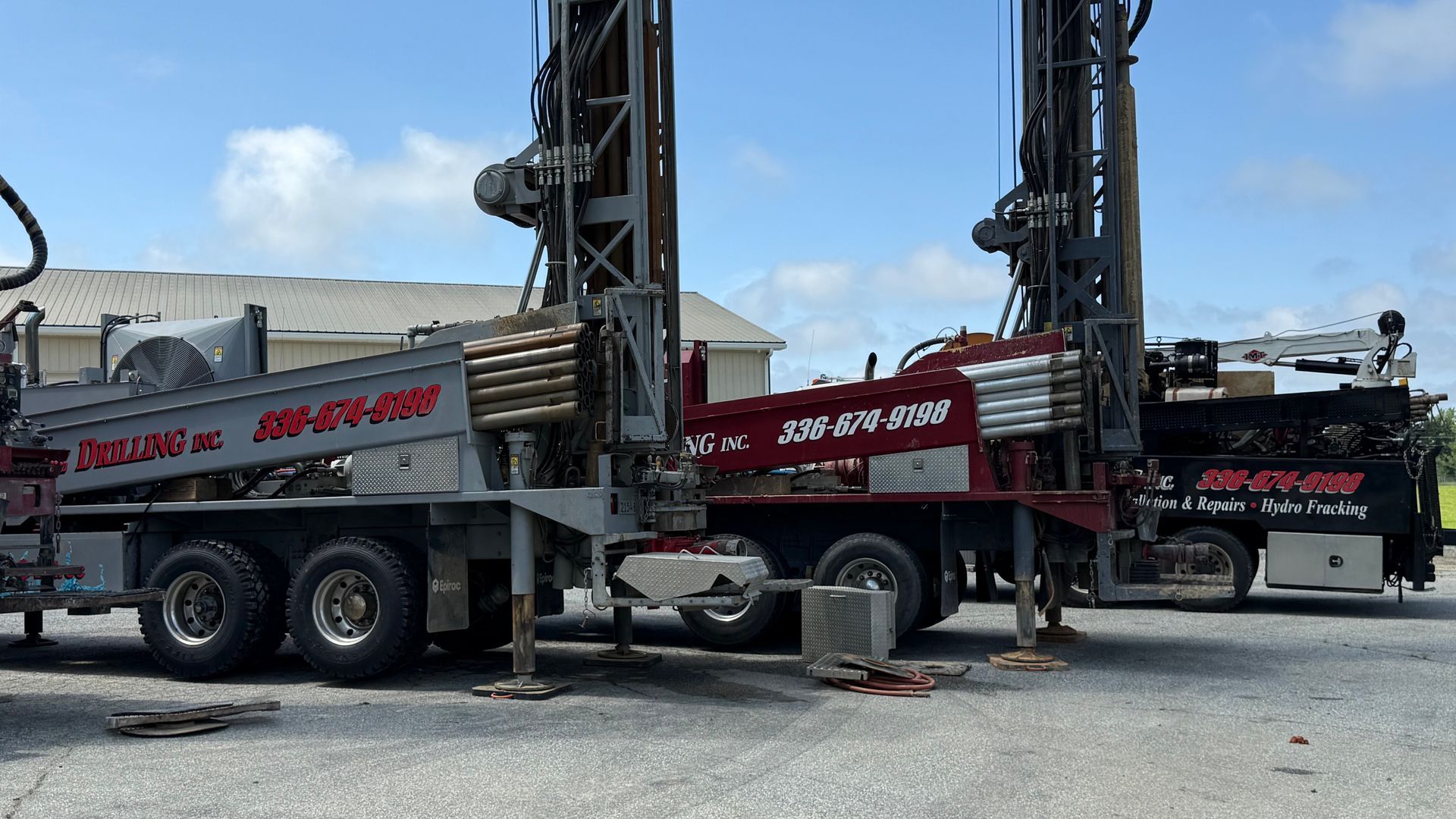 A large truck with a drilling rig attached to it is parked in a gravel lot.