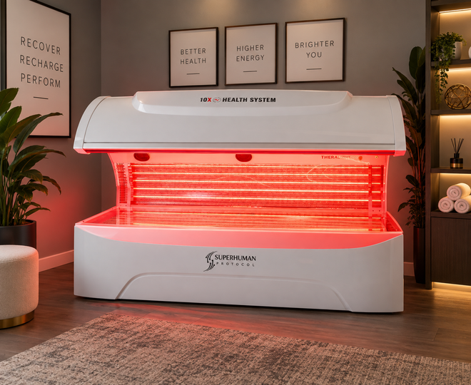 Red-lit tanning bed in a cozy showroom with framed wall art and plants