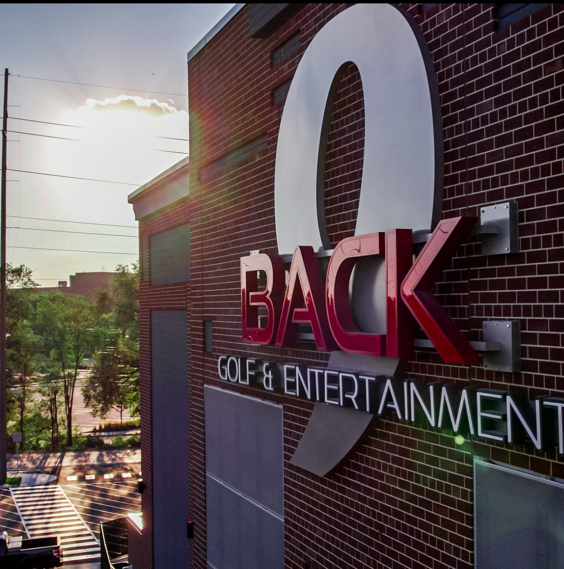 BACK Golf & Entertainment sign on a brick building in sunlight