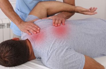 Physical therapist massaging a patient’s upper back with redness indicating pain or injury