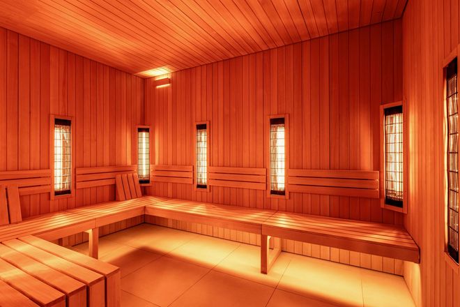 Warmly lit wooden sauna interior with bench seating and narrow windows