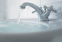 Chrome faucet with running water overflowing a white sink.