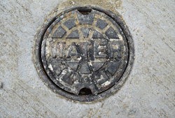 Circular water cover embedded in concrete, with the word 