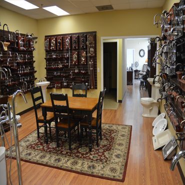 Bathroom fixtures displayed in a showroom, including sinks, faucets, and a small dining table.