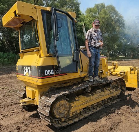 Yellow CAT D5G bulldozer in a muddy field with a person standing on the tracks