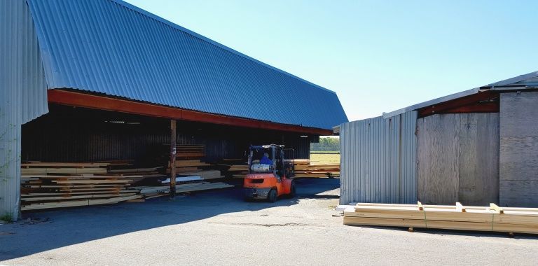 A forklift is loading wood into a warehouse.