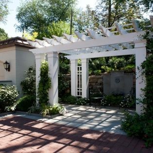 A white pergola is surrounded by trees and bushes